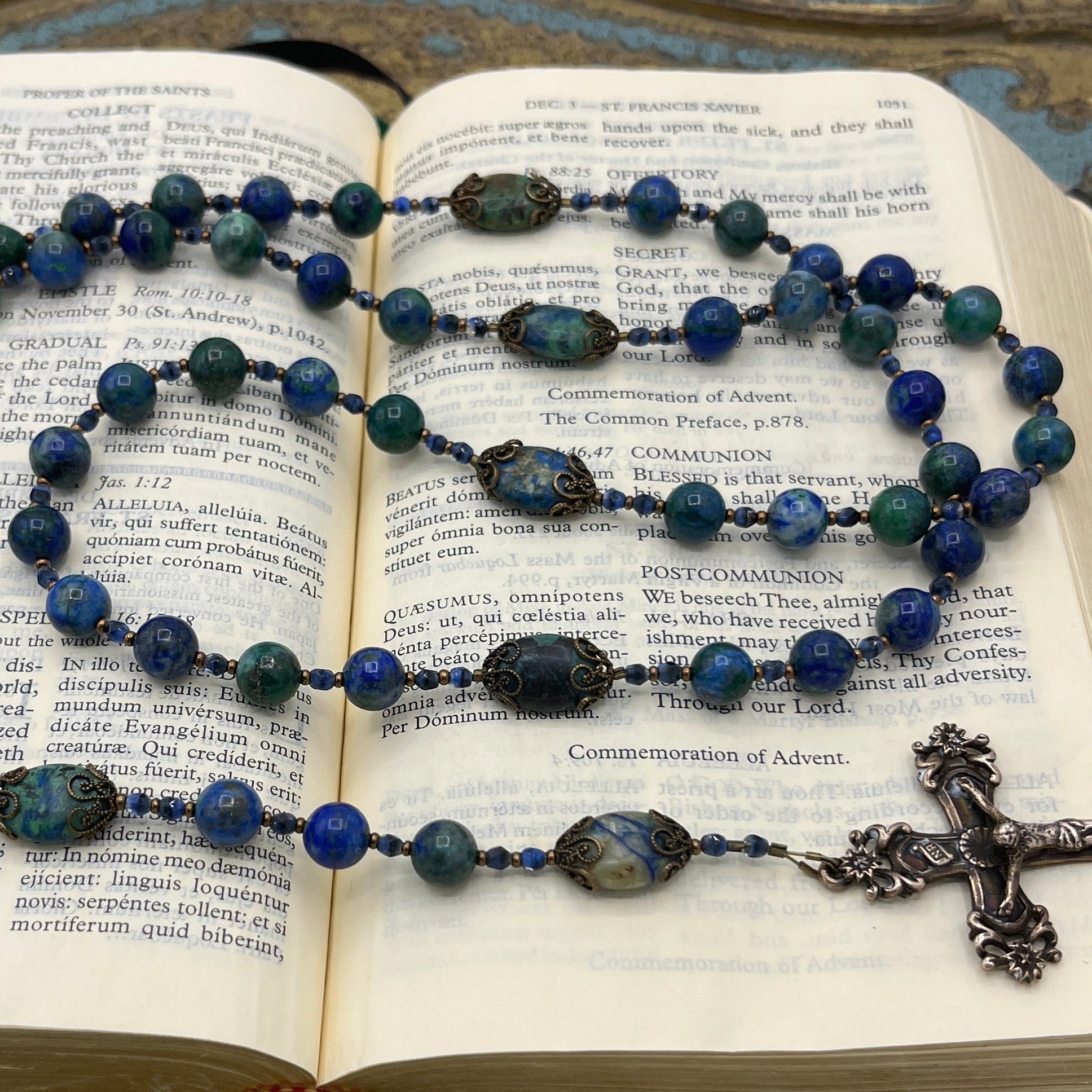 Close-up of natural Azurite and Lapis Lazuli gemstone beads in a handmade Catholic rosary displayed on a prayer book
