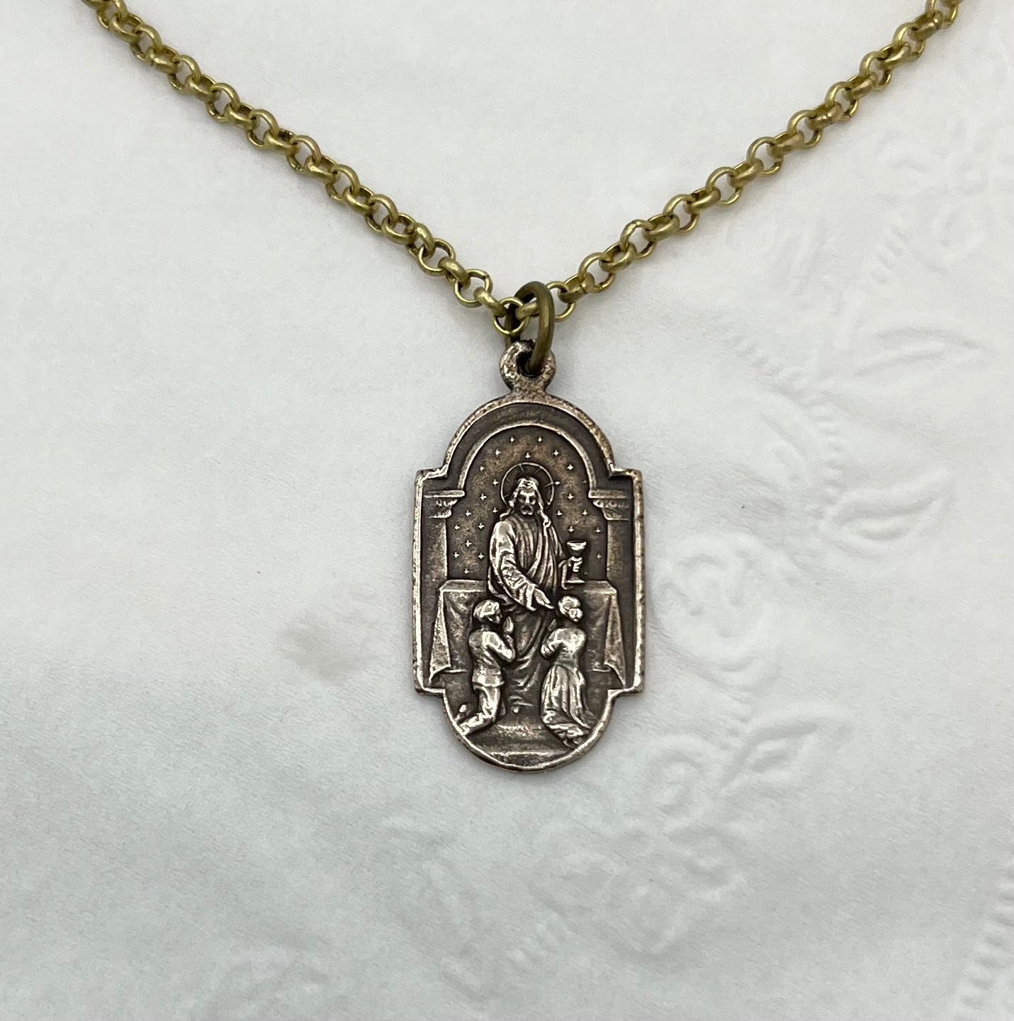 Reverse side of First Holy Communion medal necklace showing Jesus giving Holy Communion to First Communicant Children.